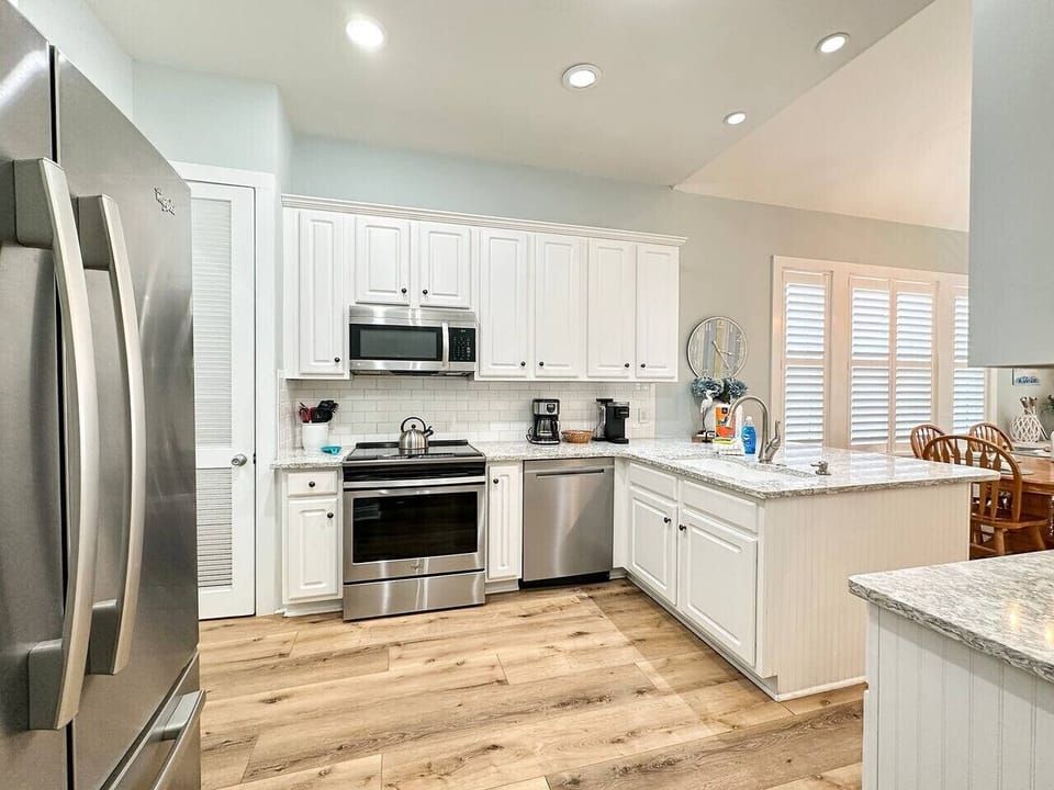 A bright, coastal kitchen featuring stainless steel appliances and generous counter space for easy meal prep and gathering.