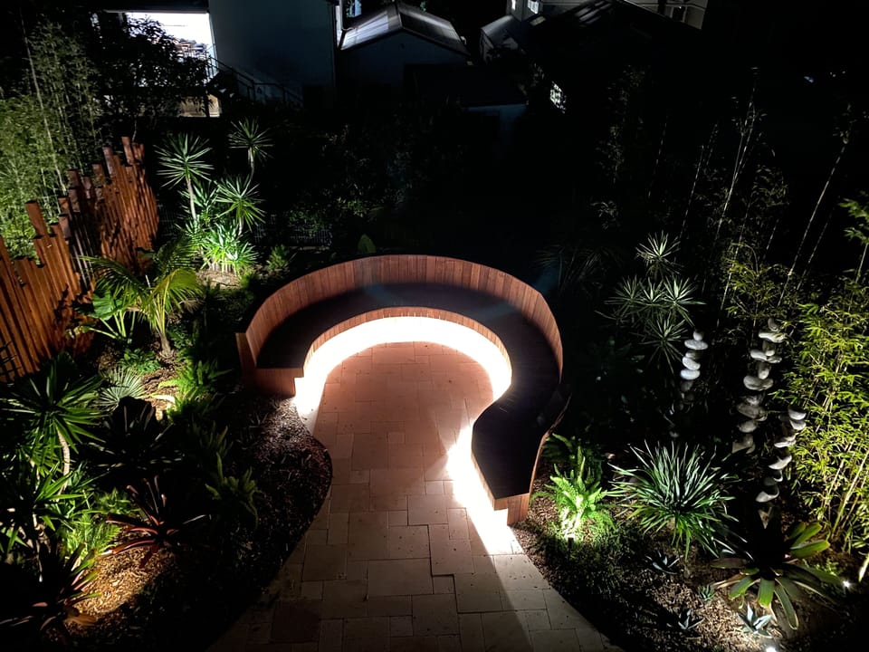 The lush garden at night with the custom seating lit from under neath