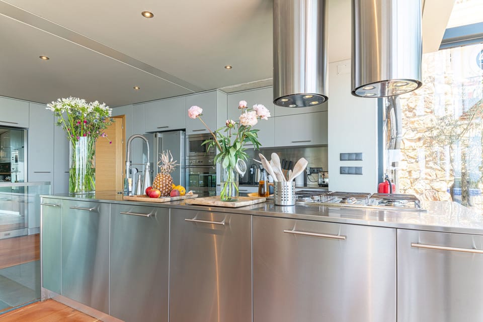 Modern kitchen with stainless steel island and pink flowers — Villa Equador, holiday villa in Cascais