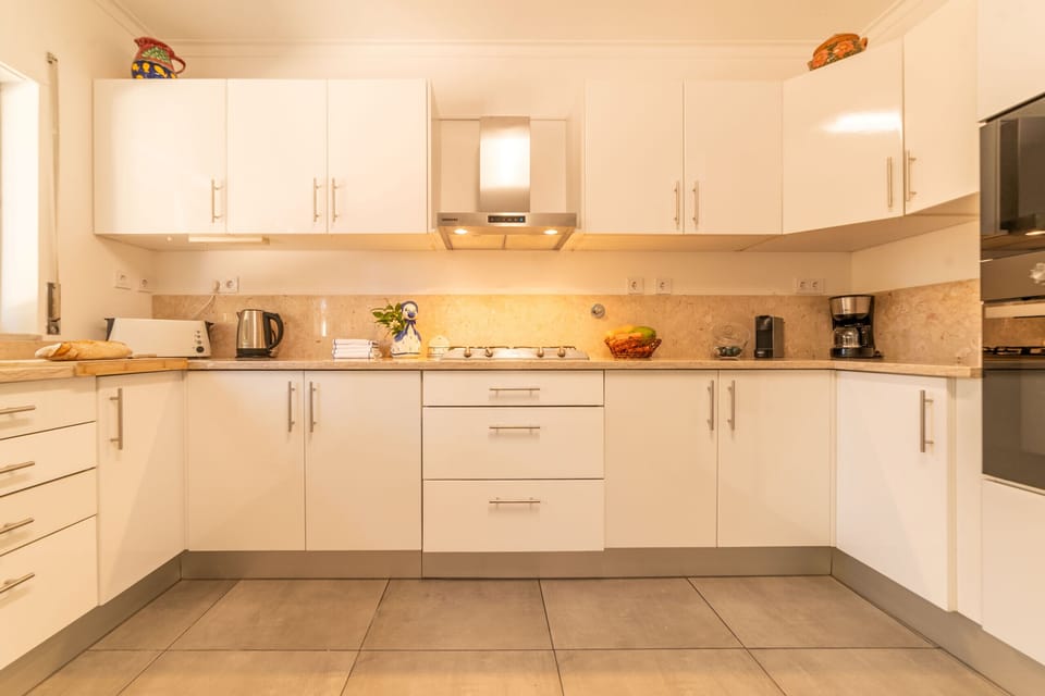 Modern white kitchen with cream stone worktops — Villa Verdizela II, luxury holiday villa in Verdizela