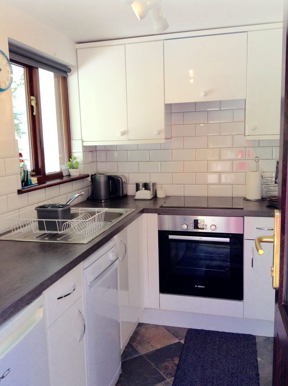 Modern kitchen with dishwasher, oven and hob. Looks out to the woods.