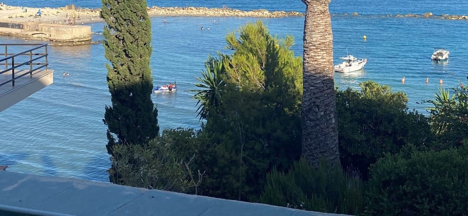 Village mini harbour with boats in the foreground (swimmers & sunbathers beyond)
