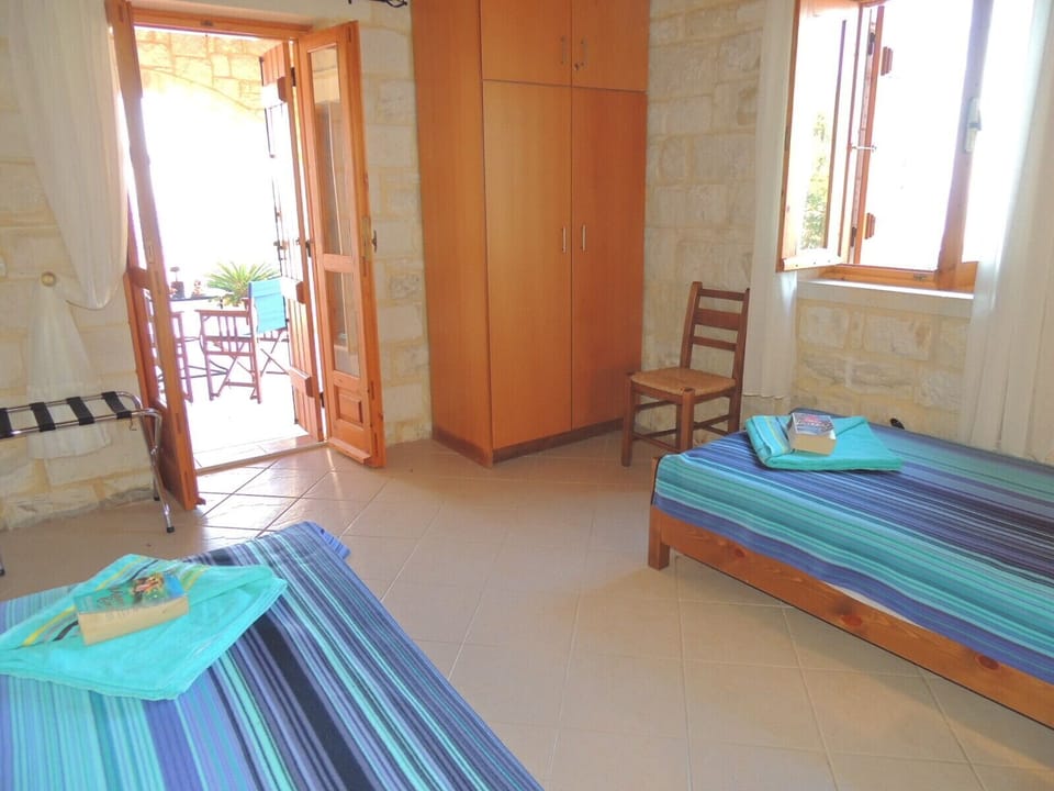 Chrisi Villa downstairs twin bedroom and doors to covered terrace and pool