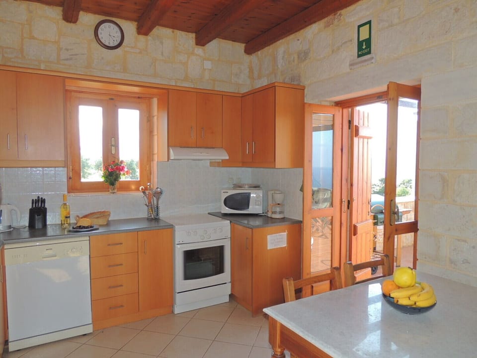 Chrisi Villa fully equipped kitchen and doors to sea view dining terrace