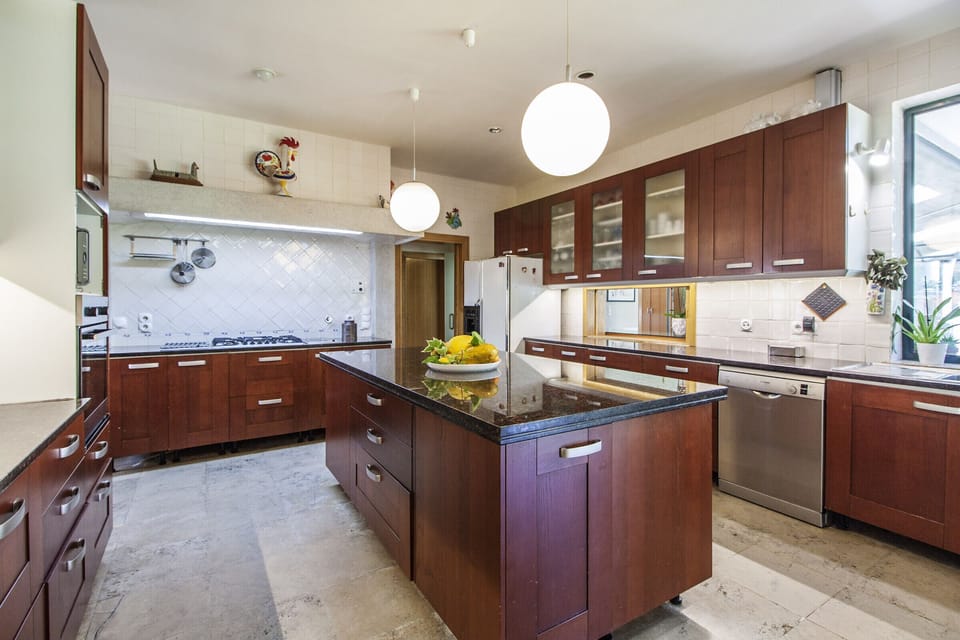 Modern kitchen with dark wood cabinetry and island — Villa do Cisne, luxury holiday villa in Herdade de Aroeira