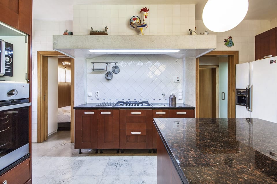 Modern kitchen with dark granite countertops and wooden cabinetry — Villa do Cisne, luxury holiday villa in Herdade de Aroeira