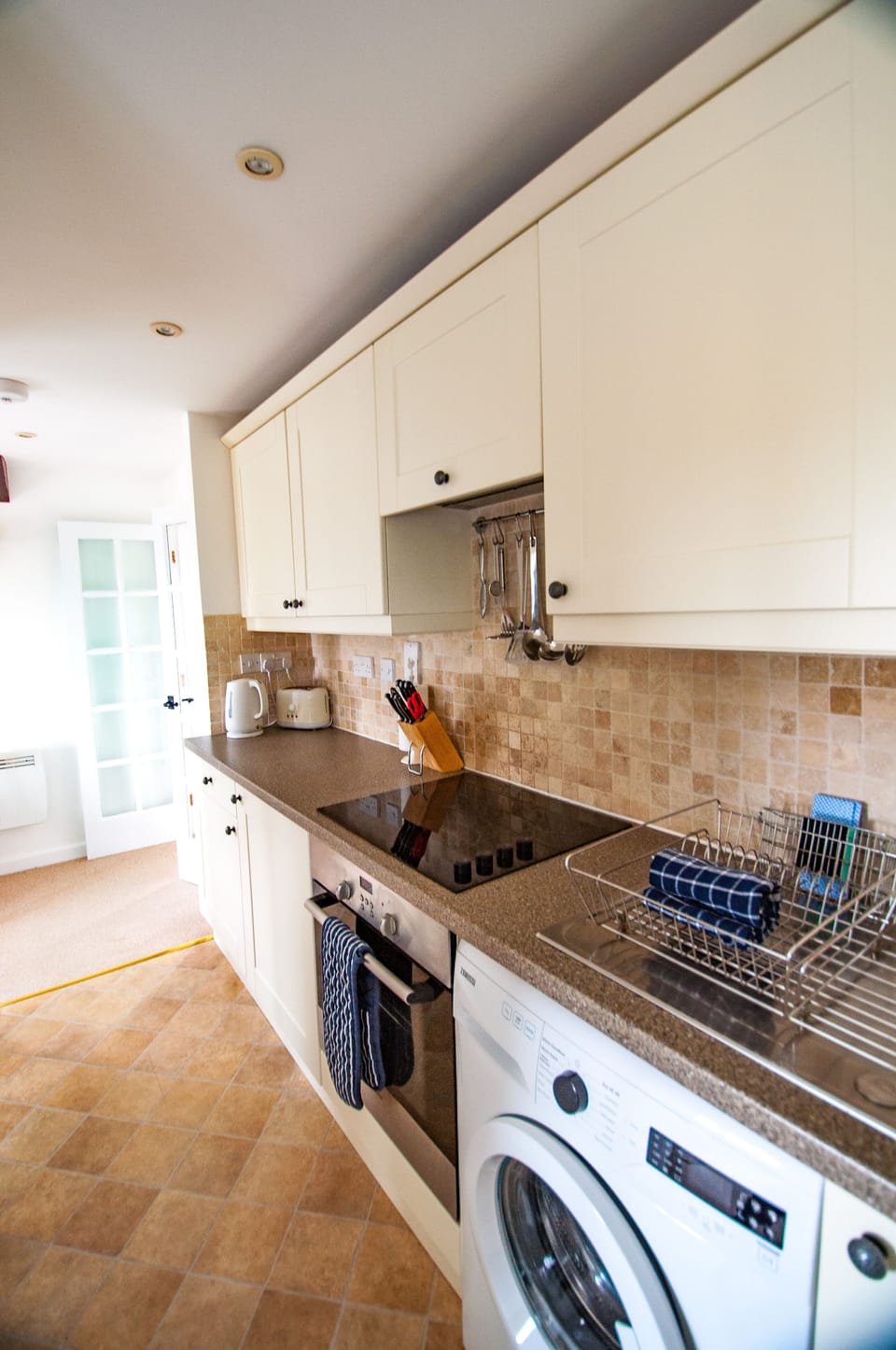 Kitchen area with fridge, electric oven/grill/hob and washing machine