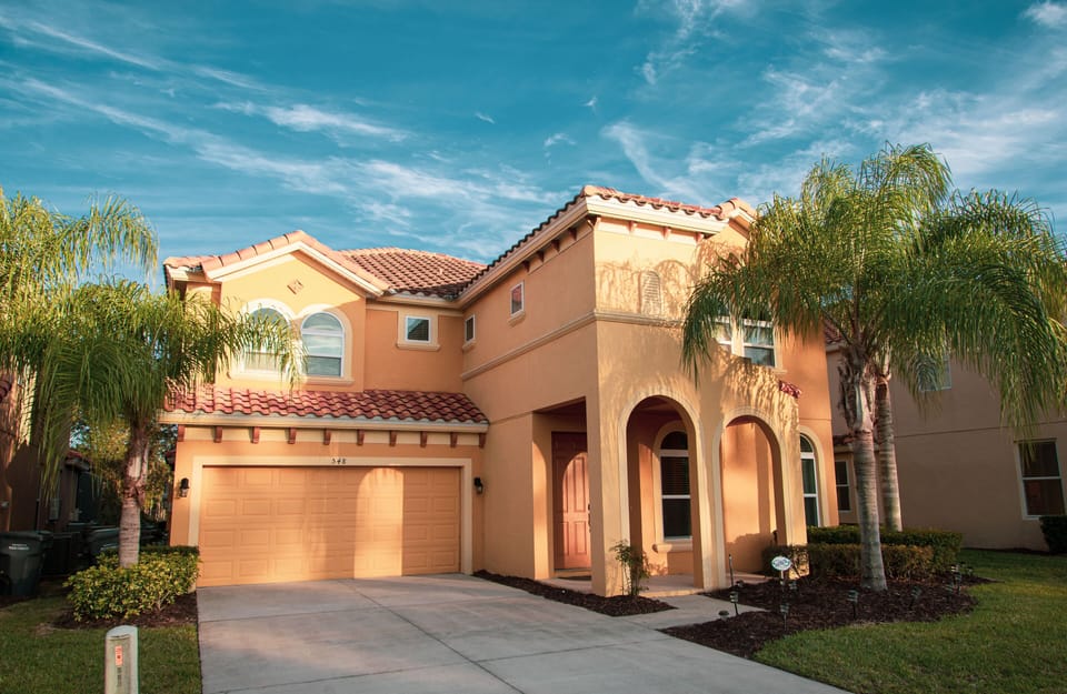 Bright, welcoming front of villa on quiet street lined with oaks and palm trees 