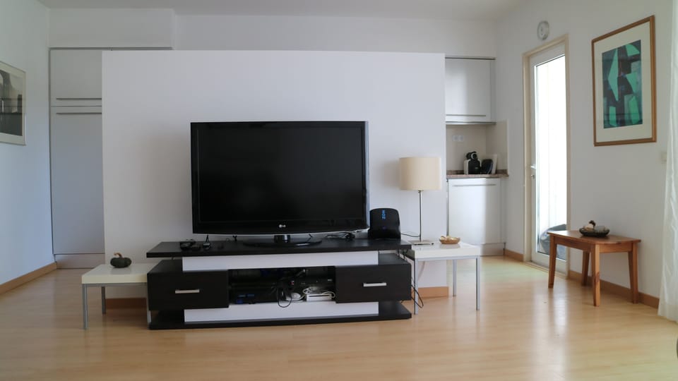 View from sofa towards TV with kitchen area beyond