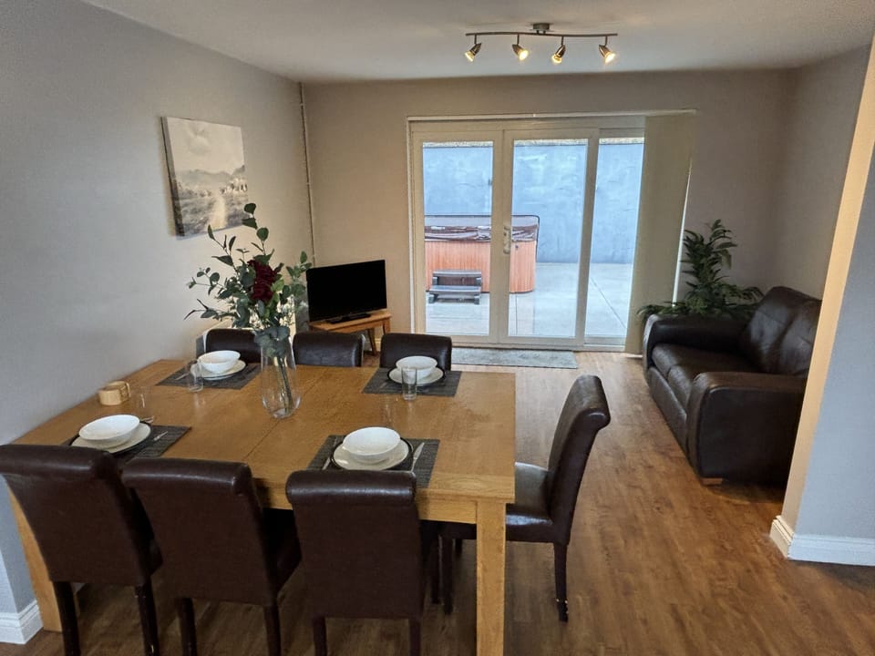 Open plan dining area and living room with smart tv leading to hot tub