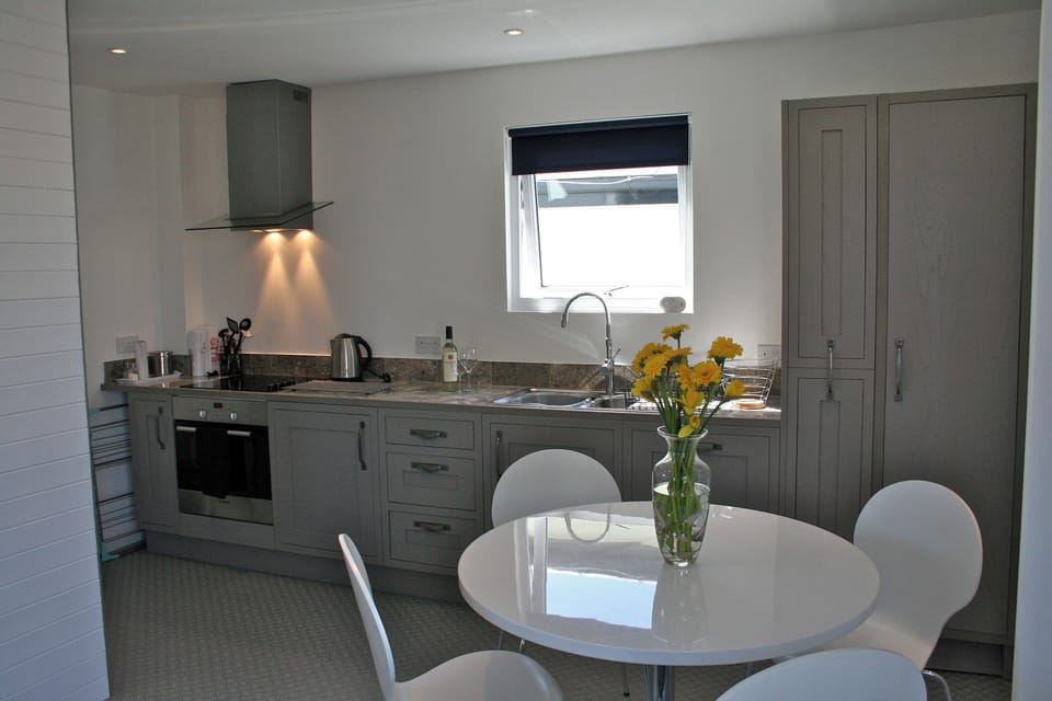 Pale grey fitted kitchen units, tiled worktop, electric oven, hob and dishwasher