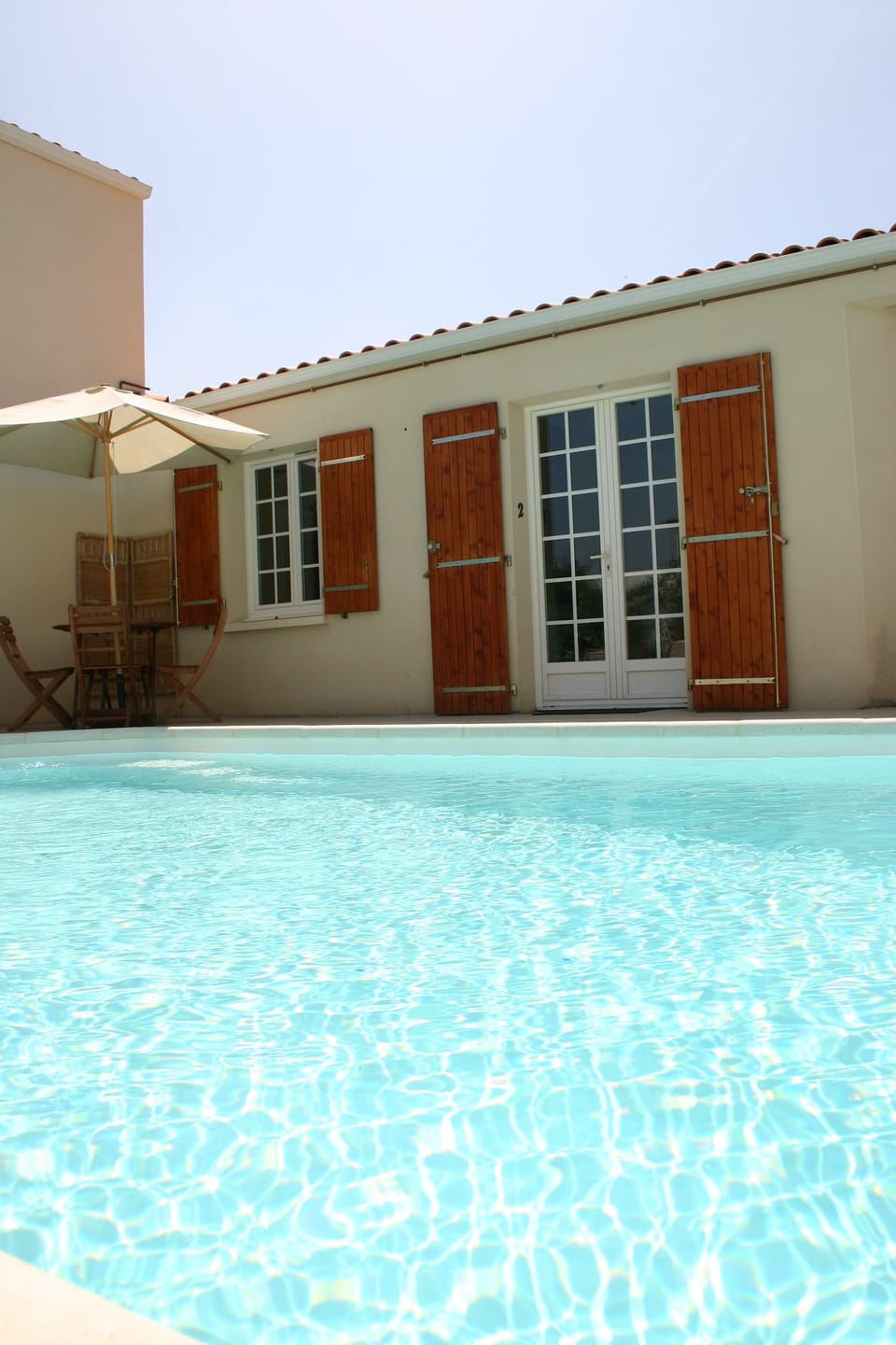 The exterior of the apartment (double door to right of image) leading to pool