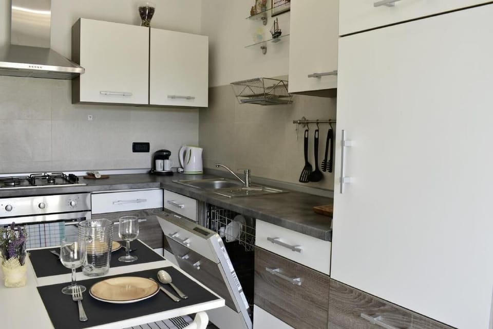 The kitchen with dishwasher, coffee maker, kettle, cooking utensils