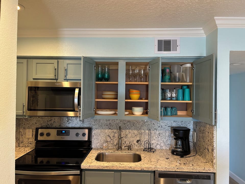 Kitchen stocked with silverware, pots, pans, cooking utensils and an ice maker.