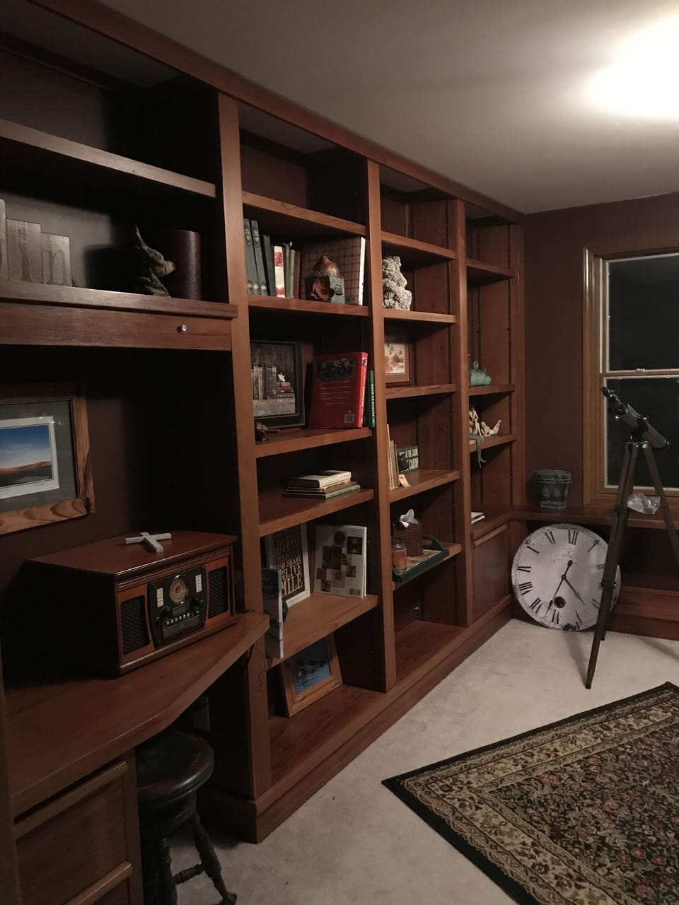 Bookshelves in den filled with books, curiosities, pictures, & phonograph/stere