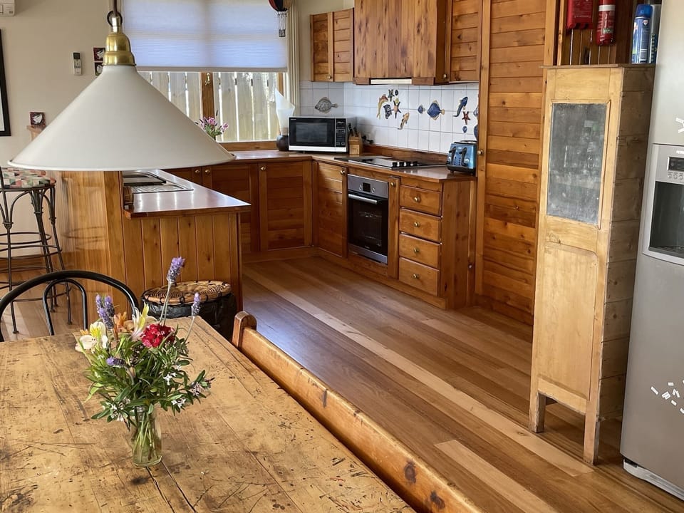 Adjustable light hanging over dining table, kitchen in background