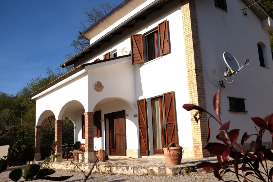 Front of house with portico and terrace above.