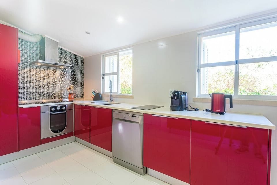 Modern kitchen with red gloss cabinetry and mosaic backsplash — Villa Flora, luxury holiday villa in Sesimbra