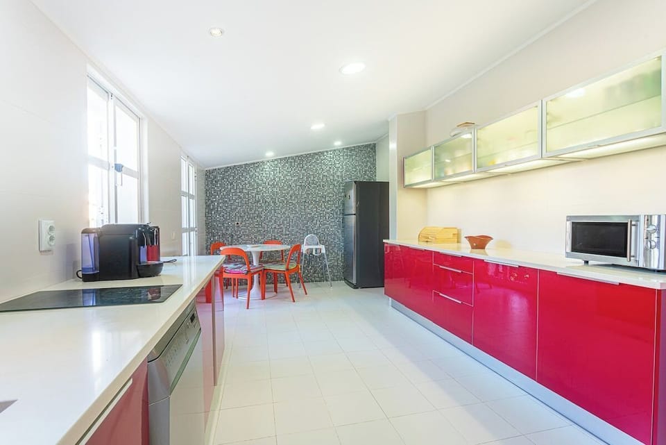 Modern kitchen with red cabinetry and mosaic backsplash — Villa Flora, luxury holiday villa in Sesimbra