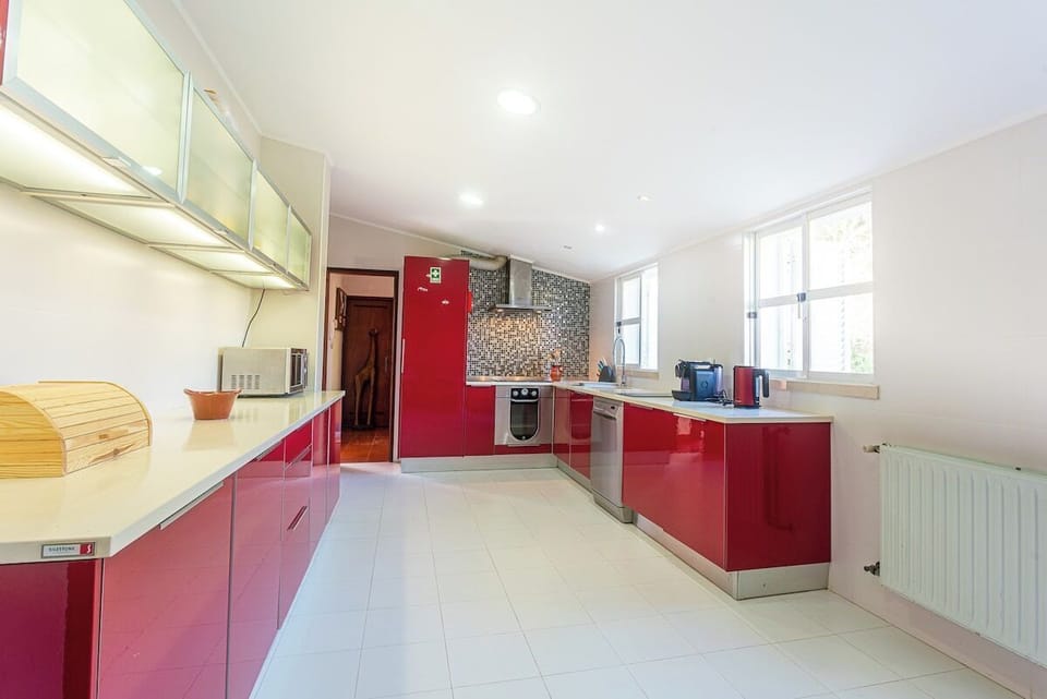 Modern kitchen with red cabinetry and island counter — Villa Flora, holiday villa in Sesimbra