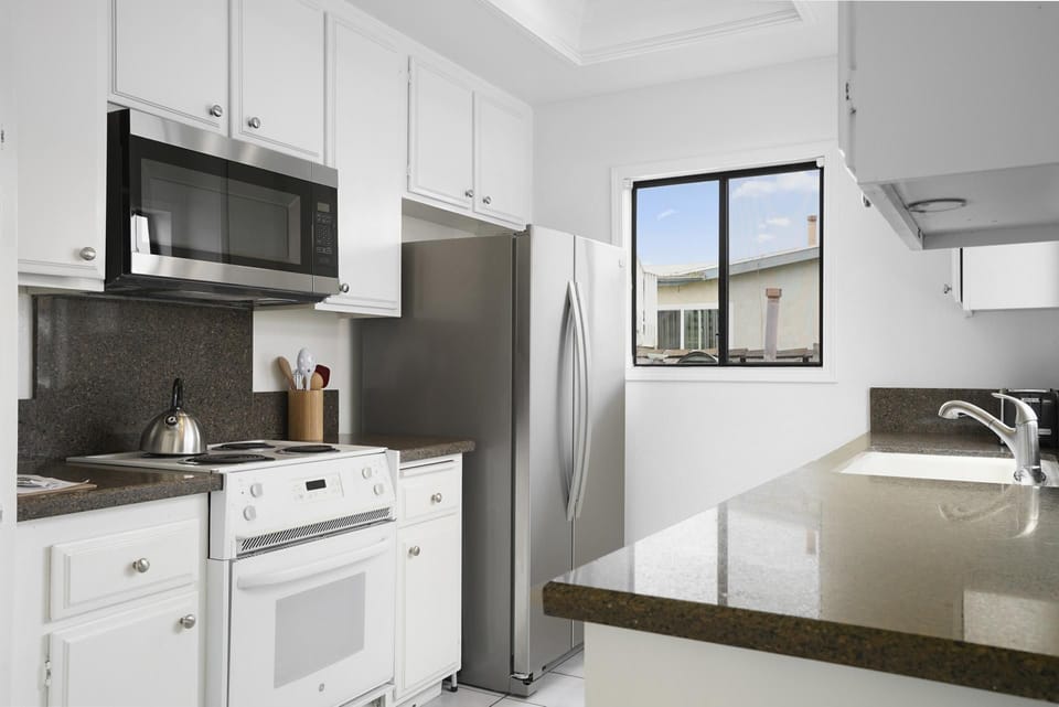 Cook with ease in the open kitchen, equipped with full appliances and a large window view of the deck
                