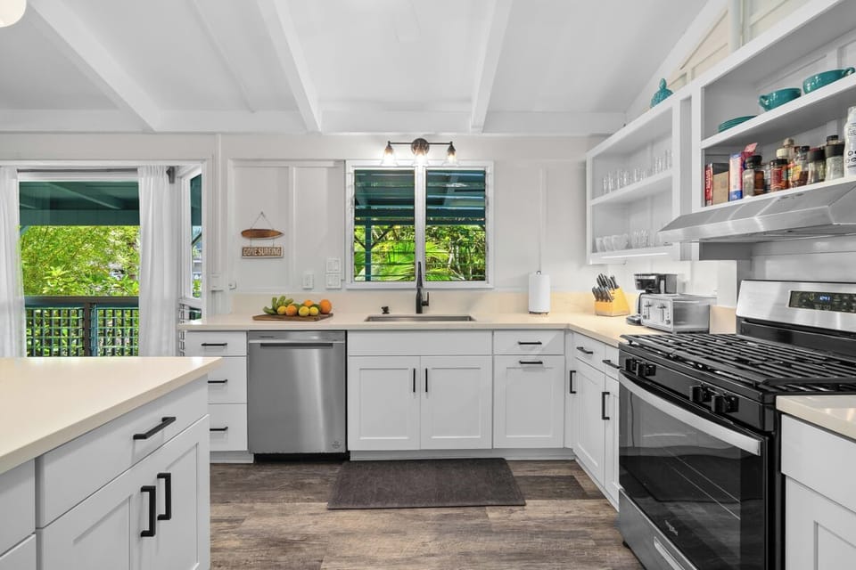 The range and open shelves sit in a bright corner, everything within easy reach.