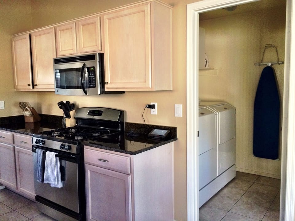 Stove, microwave, and laundry room with iron and ironing board