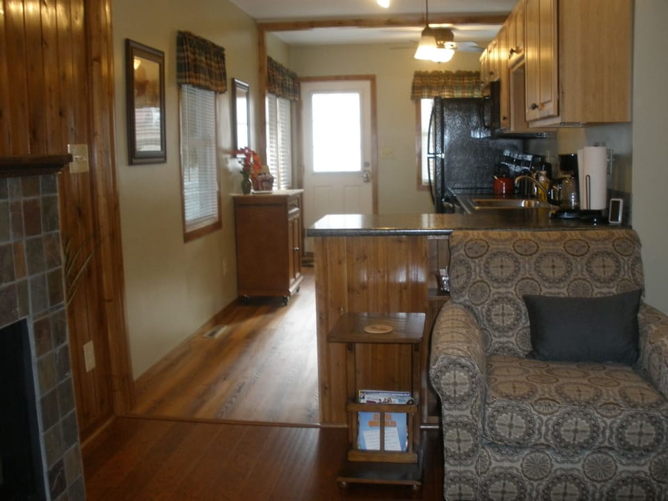 View from Living Room into Kitchen area.  Comfy chair with bookcase behind..
