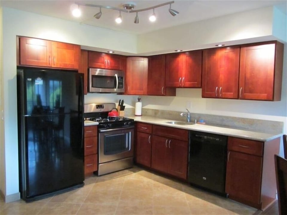 Beautiful new dark cherry wood cabinets, new appliances and travertine like tile