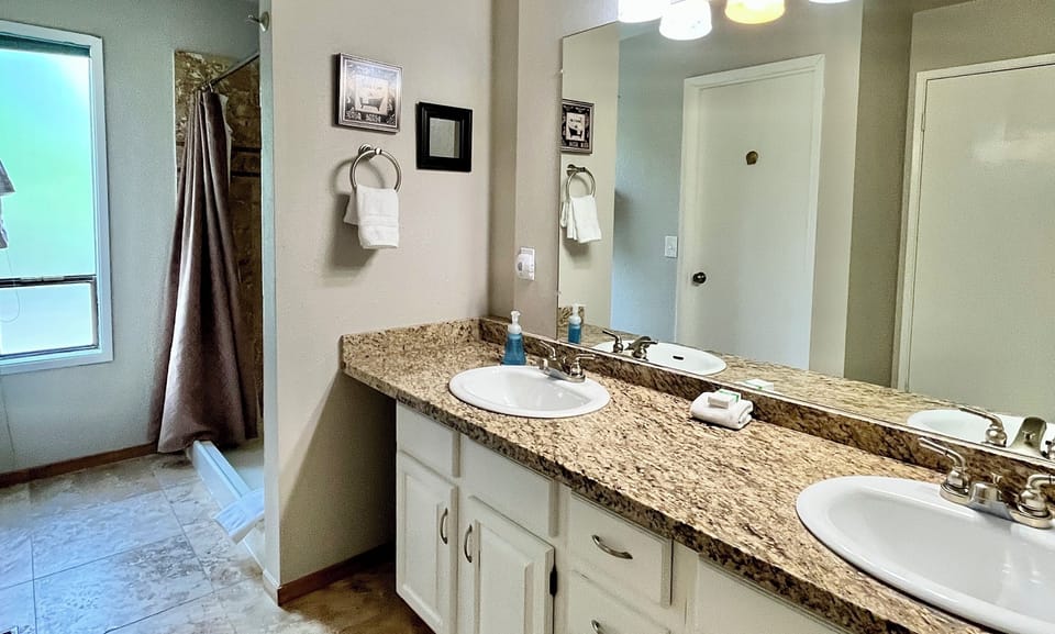 Master bathroom with large travertine shower, double sinks, and granite countertops