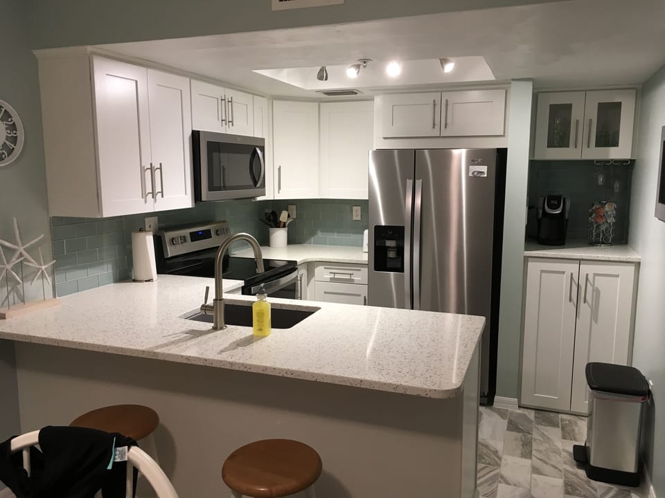 Bright white cupboards with new tile floor and quartz counters.