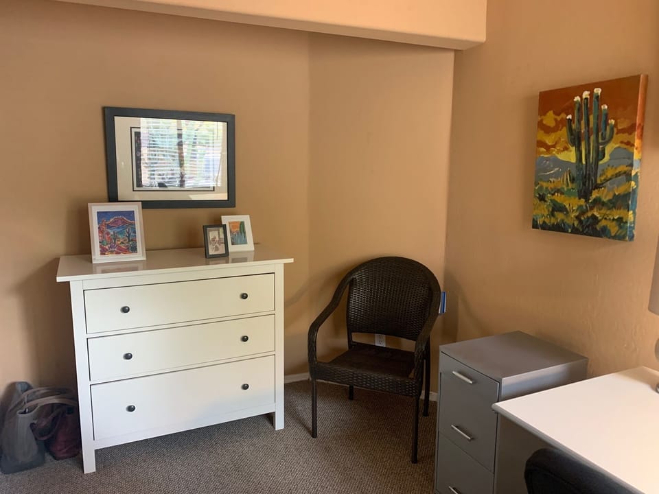 The office has a seating area next to the dresser.