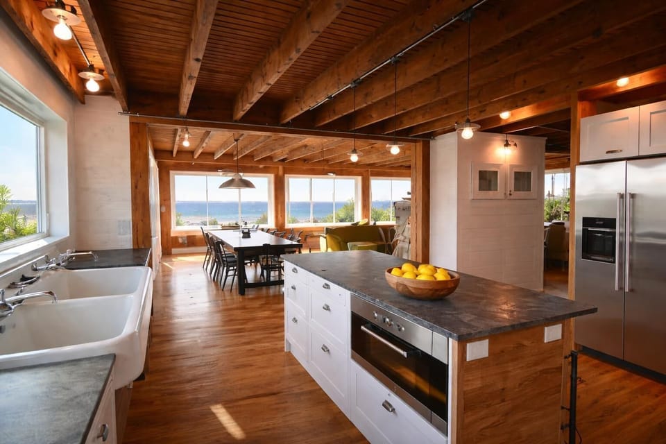 Open kitchen with island and ocean views flowing into dining and living spaces