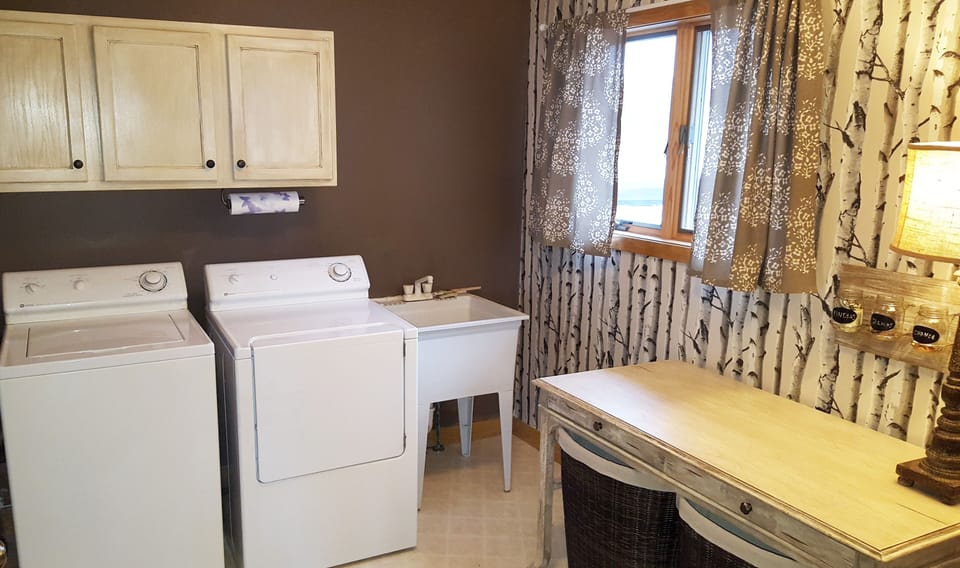 Fully equipped laundry room with utility sink and table for folding.