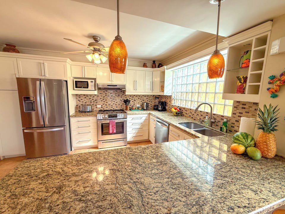 Bright, breezy kitchen with granite counters, pendant lighting, tropical view