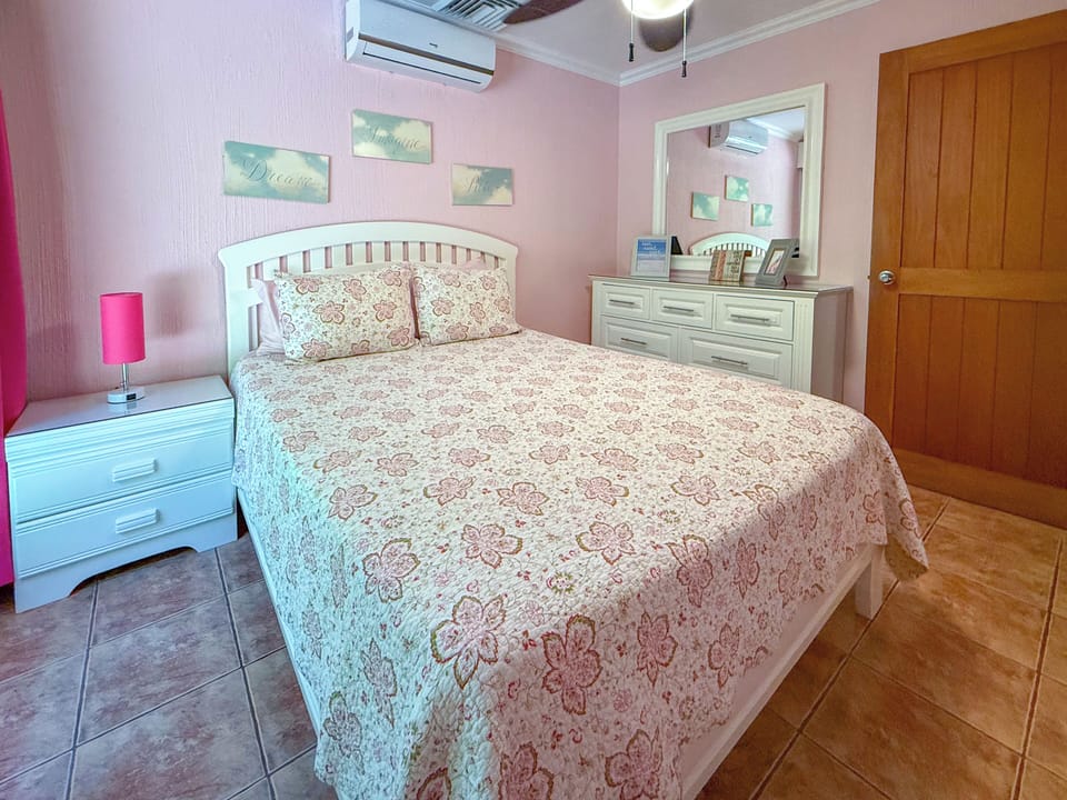 Cozy queen-bed retreat with warm tones, vintage touches, and custom dresser.