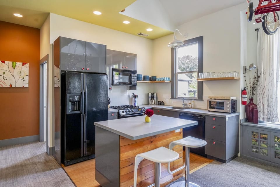 A fully stocked kitchen from coffee grinder to blender with lots of serving trays and dishes.