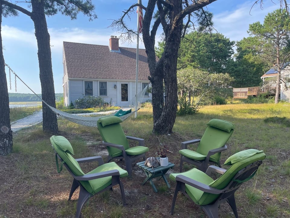 Adirondack seating for 4 alongside hammock with pillow.