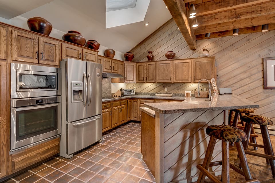 Large Kitchen and Bar with Skylight, Stone Slab Counters, and Stainless Steel Appliances