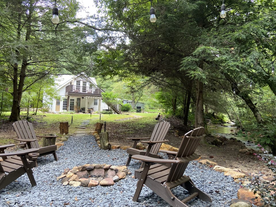 Creekside firepit looking onto the back of the house with wooden deck