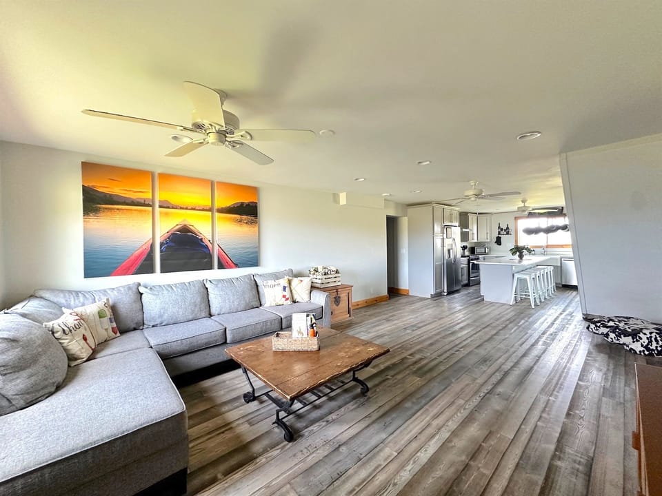 Living room in Unit B with a large TV, comfortable sectional sofa, and a cozy wood-burning stove.