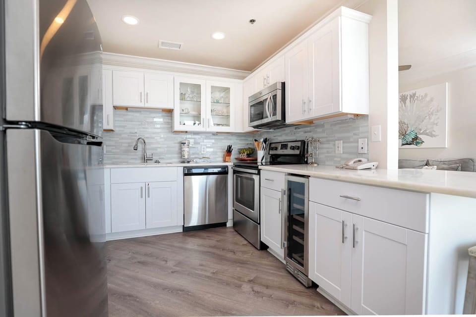 White cabinetry and marbled countertops enhance this kitchen, featuring a breakfast bar and modern appliances