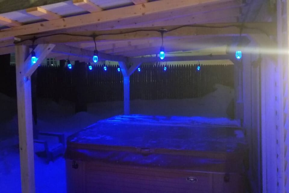 cozy outdoor hot tub, just off the outdoor space with wood stove in the garage converted to a hang out space