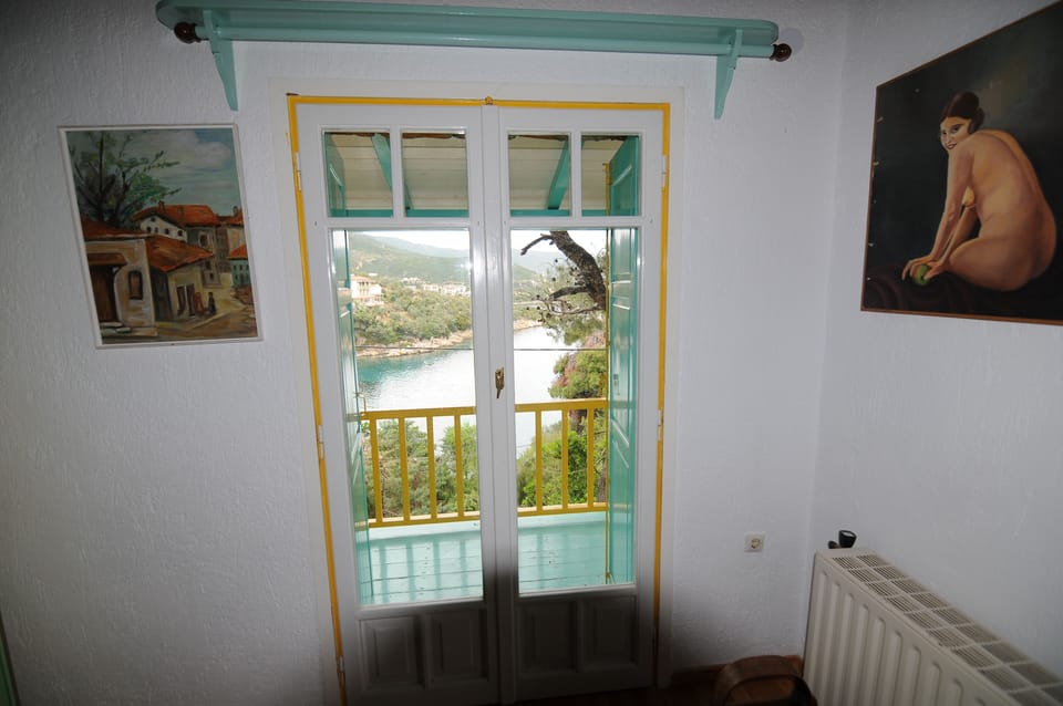 The bedroom (b) and the traditional wooden balcony. Down the cove of Agios Petro