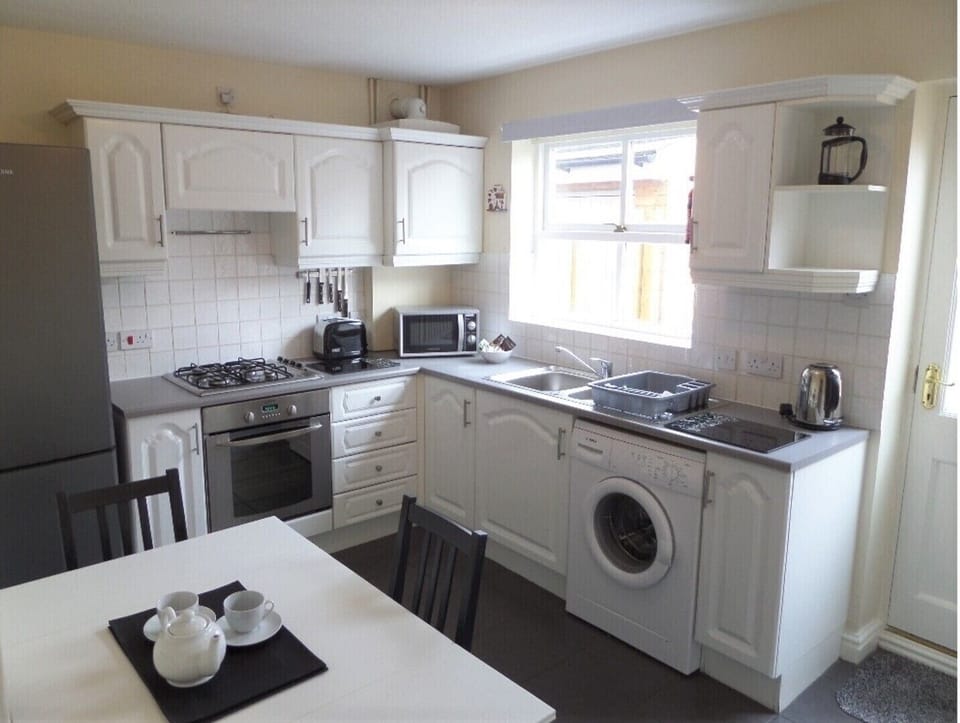 Very well equipped kitchen with table and chairs, looking out to the garden area