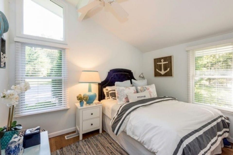 Queen bed in a cheerful guest room with a tv