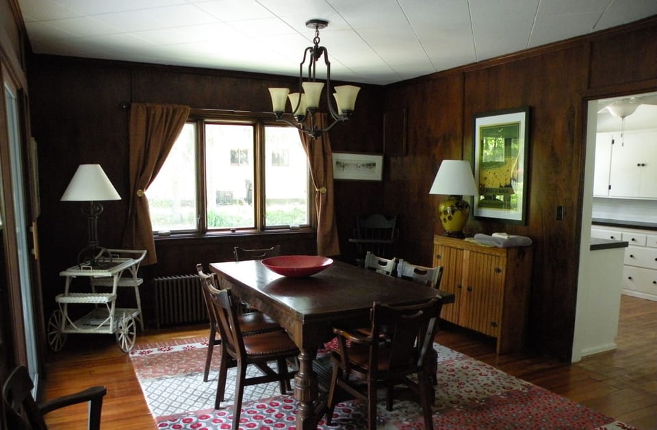 The dining area has an antique table and chairs and is bright and cheery