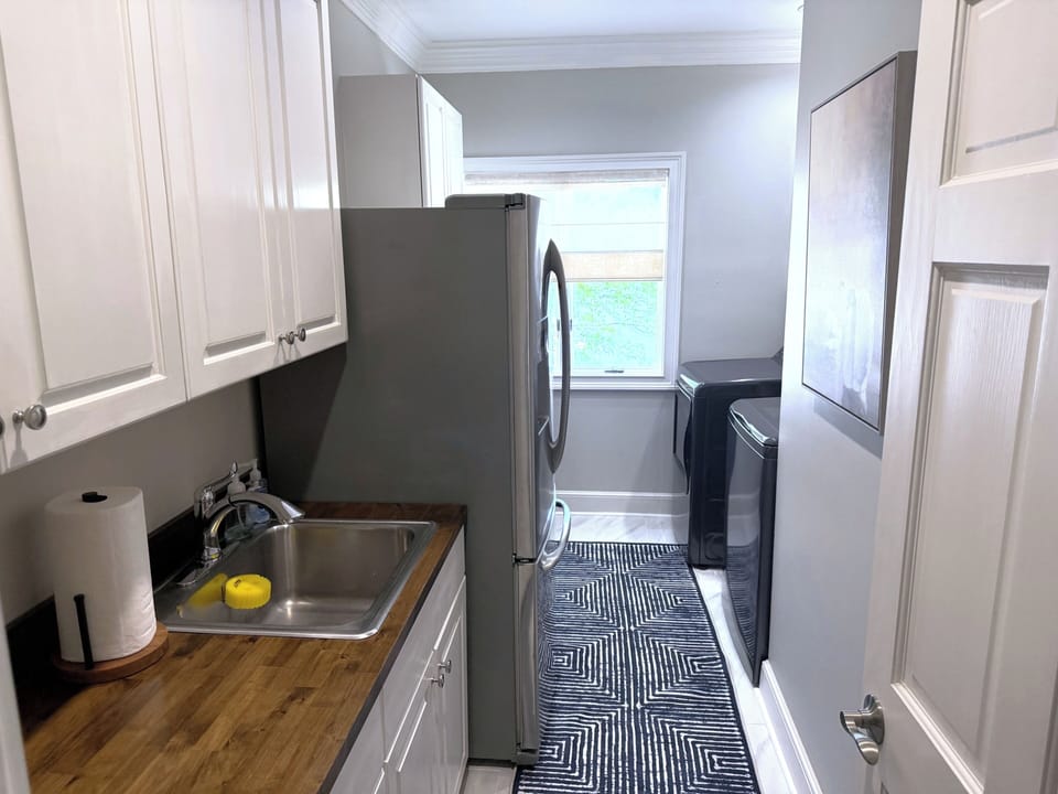 Laundry room with washer, dryer, extra refrigerator, and sink.