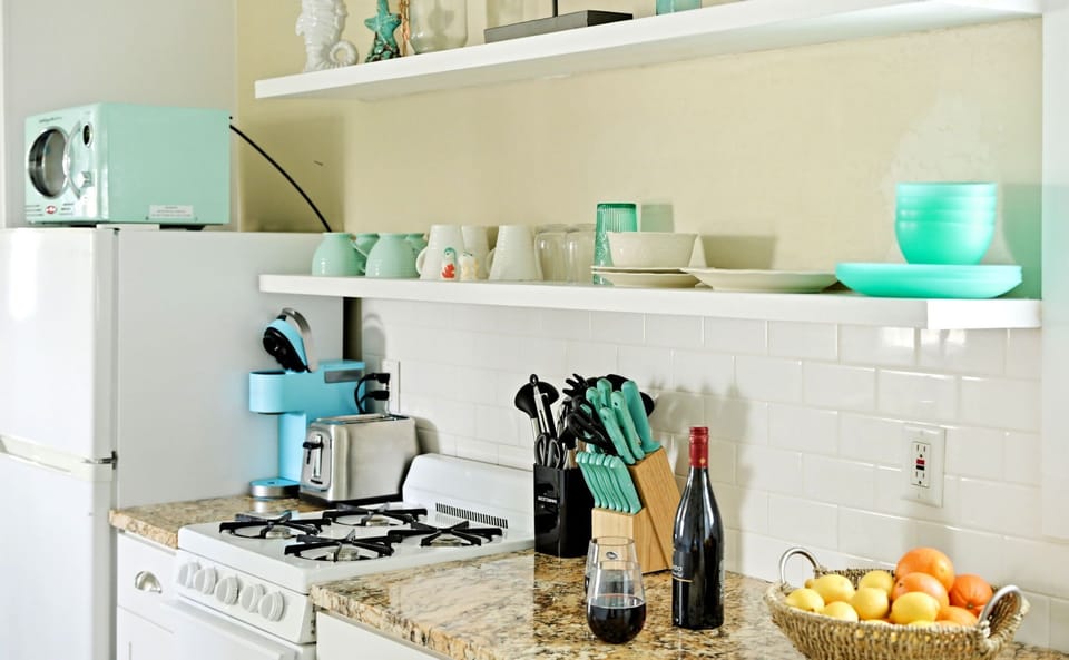 Kitchen detail with a gas range, coffee maker, and open shelving.