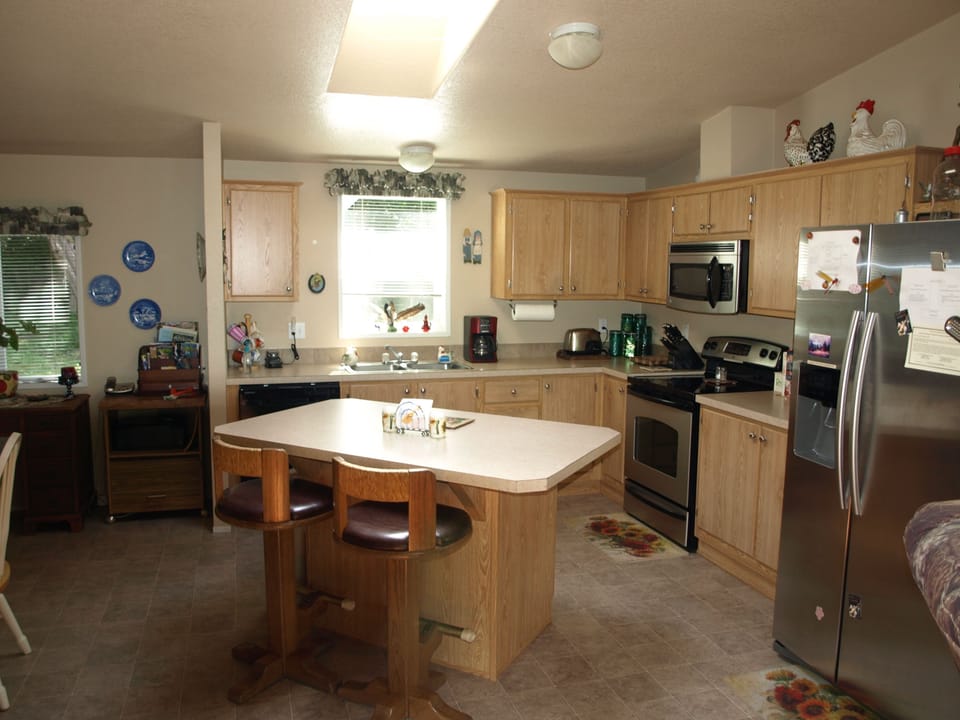 Bright and airy kitchen.  Island has 2 swiveling bar stools.